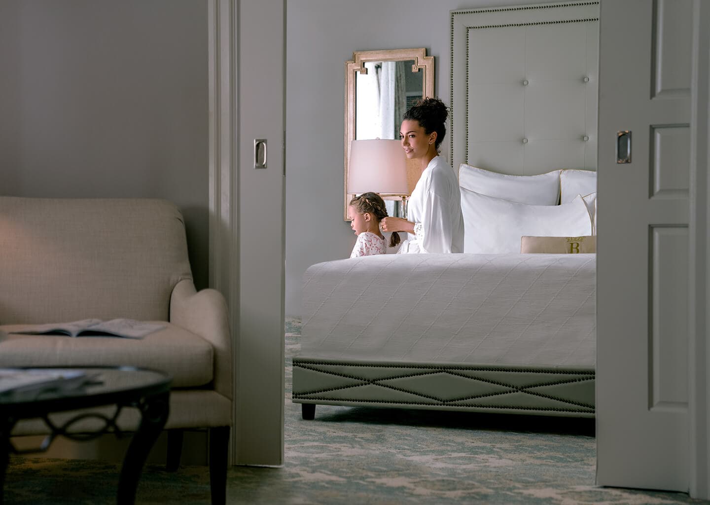 Mother braiding her daughter's hair in a modern room