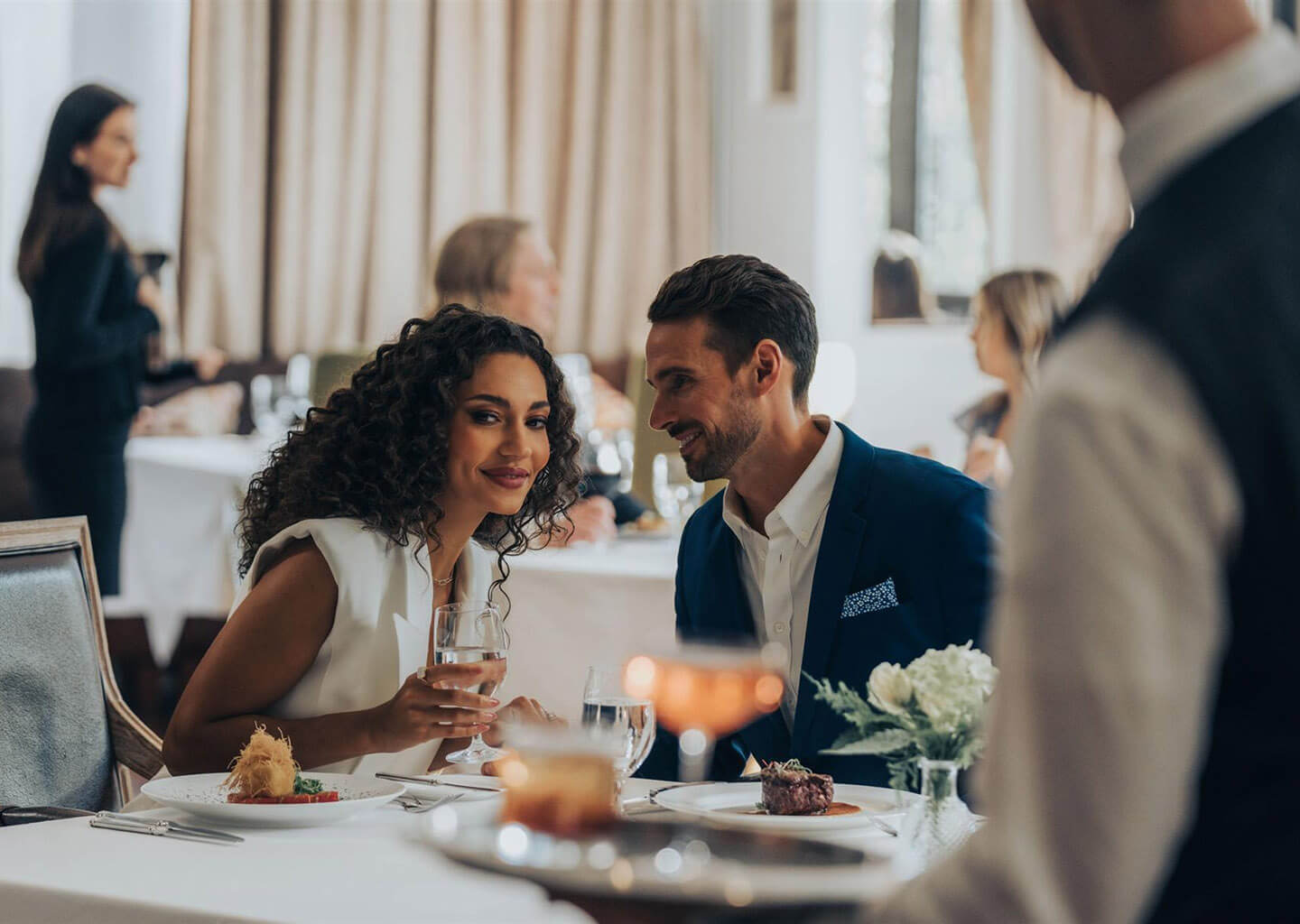 A couple dining together by candlelight with wine and main courses