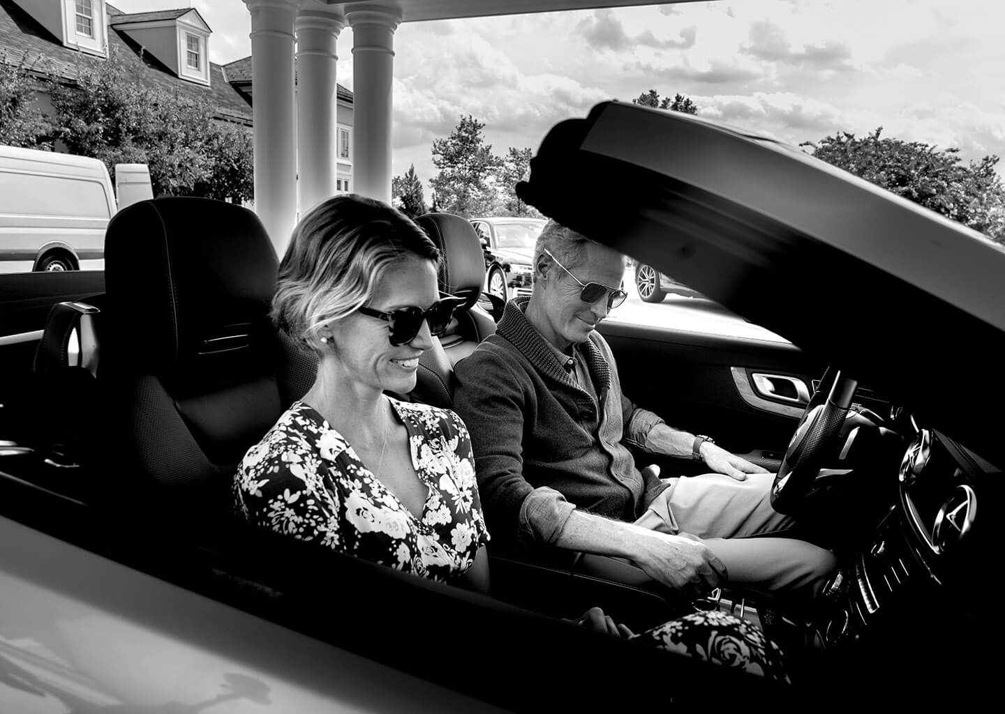 Couple smiling together in a nice car by the hotel lobby